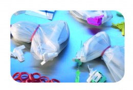 Декілька великих прозорих стерильних чохлів, закріплених червоними гумками, окремі червоні гумки-фіксатори, а також елементи, що використовуються для кріплення та точного позиціонування біопсійних голок на ультразвукових датчиках під час процедури.