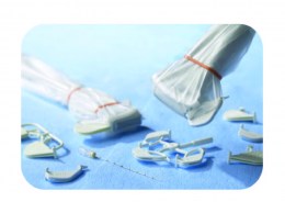 Розмаїття білих пластикових одноразових напрямних для біопсійних голок, що відрізняються формою та розміром отворів. Прозорий захисний чохол, перевязаний тонкою червоною гумкою.