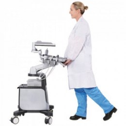 Жінка в білому халаті везе мобільний ветеринарний УЗД-апарат Chison Qbit 7 Vet. Вона штовхає його за ручку, демонструючи легкість та мобільність обладнання.